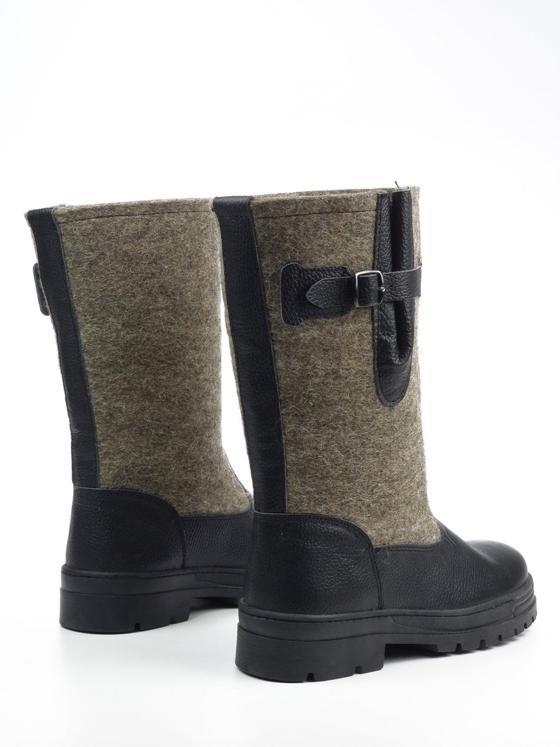 Puede incluir: Un par de botas de media ca&ntilde;a con parte superior de fieltro gris texturizado y ribetes de cuero negro. Las botas incluyen tal&oacute;n y puntera de cuero negro, una suela de goma negra con tacos y una correa de cuero con hebilla met&aacute;lica.