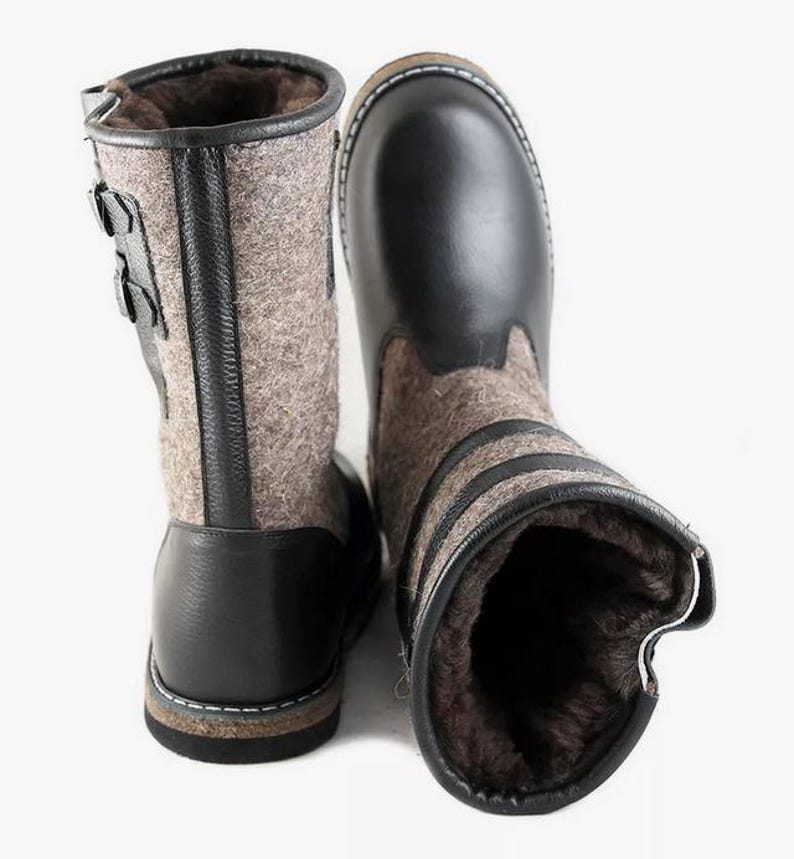 Puede incluir: Un par de botas de cuero negro y fieltro gris con cierre de hebilla. Las botas tienen una suela gruesa y est&aacute;n forradas de piel.