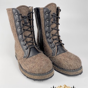 May include: A pair of mid-calf boots featuring a textured brown felted wool upper combined with black leather accents. The boots include black laces threaded through silver-toned metal eyelets, a black side zipper, and a thick, dark, textured rubber sole.