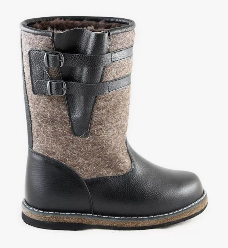 Puede incluir: Botas de cuero negro y fieltro gris con cierre de hebilla. Las botas tienen una suela gruesa de goma.