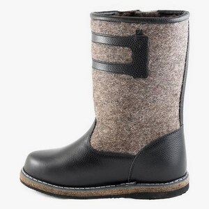 Puede incluir: Botas de fieltro negras con suela de cuero y una correa de cuero negra en la parte superior de la bota.