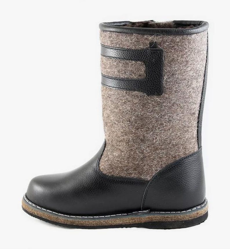 Puede incluir: Botas de fieltro negras con suela de cuero y una correa de cuero negra en la parte superior de la bota.