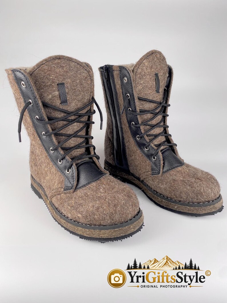 May include: A pair of brown felt boots featuring black leather trim, black laces, and black side zippers. The boots have a textured brown wool-like exterior, black metal eyelets, and a thick black rubber sole with visible stitching detail.