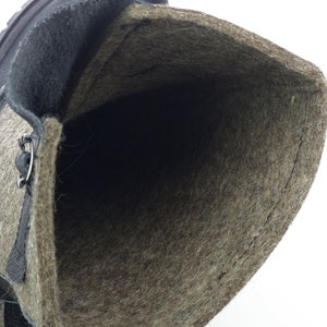 Puede incluir: Una bota alta con exterior de cuero marr&oacute;n oscuro y un forro grueso de lana afieltrada de color marr&oacute;n claro con textura. La bota tiene un ojal met&aacute;lico visible para los cordones y una suela de goma resistente de color marr&oacute;n oscuro.