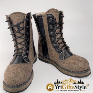 May include: A pair of mid-calf boots crafted from brown felted material with black leather accents. The boots feature black laces, silver-toned eyelets, and a side zipper closure. The soles are black with visible stitching along the base.