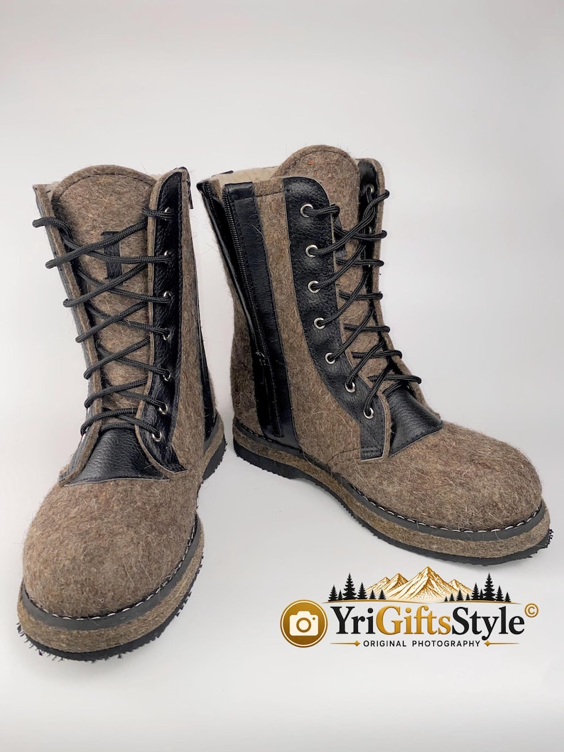 May include: A pair of mid-calf boots crafted from brown felted material with black leather accents. The boots feature black laces, silver-toned eyelets, and a side zipper closure. The soles are black with visible stitching along the base.