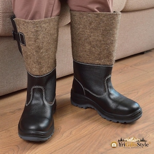Könnte beinhalten: Wadenhohe Stiefel mit schwarzem, strukturiertem Leder im unteren Bereich, weißen Kontrastnähten und einem Schaft aus brauner Filzwolle. Die Stiefel verfügen über einen seitlichen schwarzen Riemen mit Schnalle und eine dunkelgraue Profilsohle.