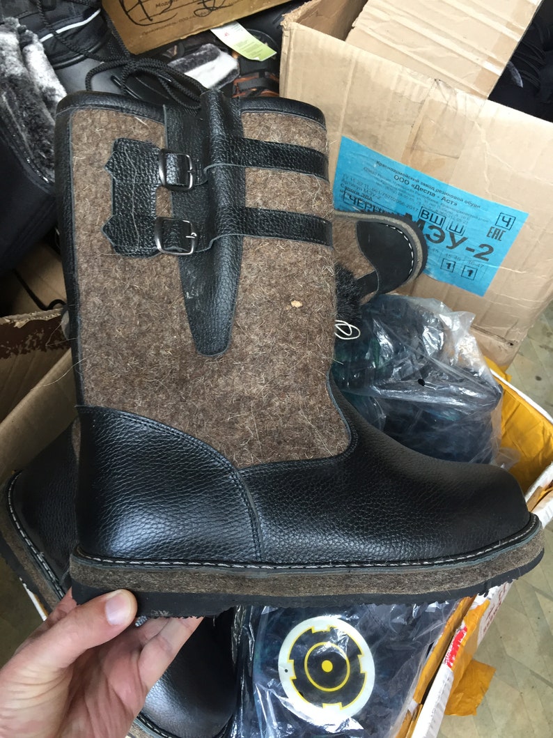 Puede incluir: Botas de fieltro marr&oacute;n y negro con parte superior de cuero negro y suela de goma gruesa. Las botas tienen dos hebillas negras en el lateral.