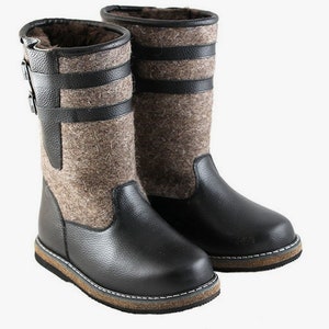 Puede incluir: Botas de cuero negro con forro de fieltro marr&oacute;n y cierre de hebilla. Las botas tienen una suela gruesa marr&oacute;n.