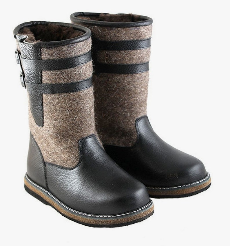 Puede incluir: Botas de cuero negro con forro de fieltro marr&oacute;n y cierre de hebilla. Las botas tienen una suela gruesa marr&oacute;n.