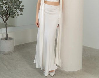May include: A white halter top with a draped cowl neckline and a matching white maxi skirt. The top and skirt are made of a silky fabric.