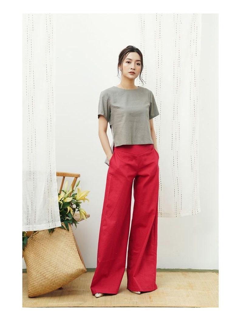 May include: A woman is wearing a gray short-sleeved top and wide-legged red pants.