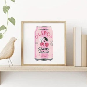 Könnte beinhalten: Ein gerahmter Druck einer rosa und weißen Dose Olipop Cherry Vanilla Sparkling Tonic. Die Dose zeigt eine Kirsche und eine Blume.