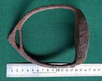 May include: A rusty metal stirrup with a rounded shape, measuring approximately 45 cm in length. The stirrup is on a green surface with a ruler for scale.