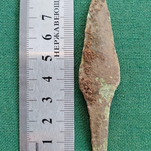 Peut inclure: Une pointe de flèche en métal rouillée de couleur brune avec une pointe pointue. La pointe de flèche mesure environ 7 cm de long et est mesurée à l'aide d'une règle.