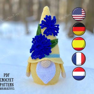 Può includere: Uno schema all'uncinetto per un gnomo giallo con una corona di fiori blu. Lo schema è disponibile in inglese, tedesco, spagnolo, francese e olandese. Lo schema è disponibile per il download in PDF.