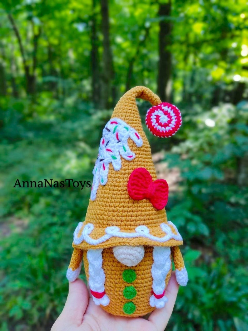 May include: A gingerbread gnome crochet doll with white icing, red and white candy, and green sprinkles. The gnome is wearing a red bow and has white yarn hair.