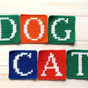 Może przedstawiać: Kwadraty na szydełku z wyhaftowanymi słowami "DOG CAT" białą nicią. Kwadraty są zielone, pomarańczowe, niebieskie i czerwone.