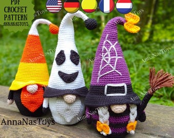 May include: Three crocheted Halloween gnomes. The gnome on the left is wearing a candy corn hat, the middle gnome is wearing a ghost hat, and the gnome on the right is wearing a purple witch hat with a black brim and a spiderweb design. The witch gnome has a broom and two orange bows in her hair.