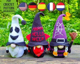 May include: Three crocheted Halloween gnomes. The gnome on the left is white with a ghost face and black hat. The gnome in the middle is black with a red heart and a hat that says "Happy Hello Ween". The gnome on the right is purple with a witch hat and a broom.