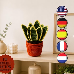 Puede incluir: Una planta de serpiente tejida a ganchillo en una maceta color terracota con hojas verde oscuro y bordes amarillos. Una insignia roja en forma de estrella a la izquierda muestra el texto PDF CROCHET PATTERN ANNANASTOYS. Cinco iconos de banderas.
