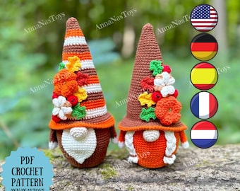 May include: Two handmade crochet gnomes with conical hats and white beards. One gnome has a striped orange and brown hat, the other has a solid brown hat. Both gnomes are decorated with autumn-themed flowers and leaves. The text "PDF CROCHET PATTERN ANNANASTOYS" is visible.
