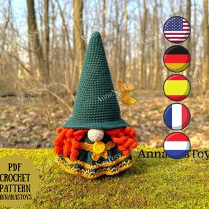 以下が含まれることがあります： 緑の尖った帽子、オレンジ色のひげ、黄緑色の衣装を着た手作りのかぎ針編みのノーム。ノームは白い鼻と帽子に小さな黄色の星が付いています。画像には「PDF CROCHET PATTERN ANNANASTOYS」というテキストも含まれています。