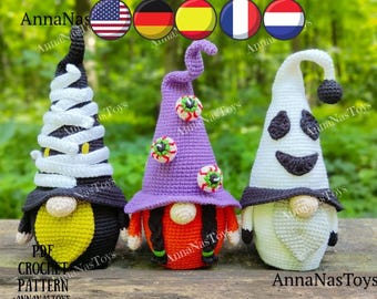 May include: Three crocheted Halloween gnomes. The gnome on the left is a mummy gnome with a black hat and white bandages. The gnome in the middle is a witch gnome with a purple hat and orange hair. The gnome on the right is a ghost gnome with a white hat and a black smiling face.