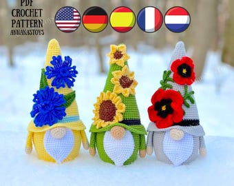 May include: Three crocheted gnomes with different flower accents. The gnome on the left has blue flowers, the middle gnome has yellow flowers, and the gnome on the right has red flowers.  PDF CROCHET PATTERN ANNANASTOYS