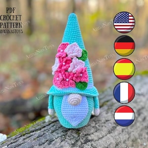 May include: A crochet pattern for a gnome with a blue hat and pink flowers. The pattern is available in PDF format and includes instructions for crocheting the gnome in English, German, Spanish, French, and Dutch.