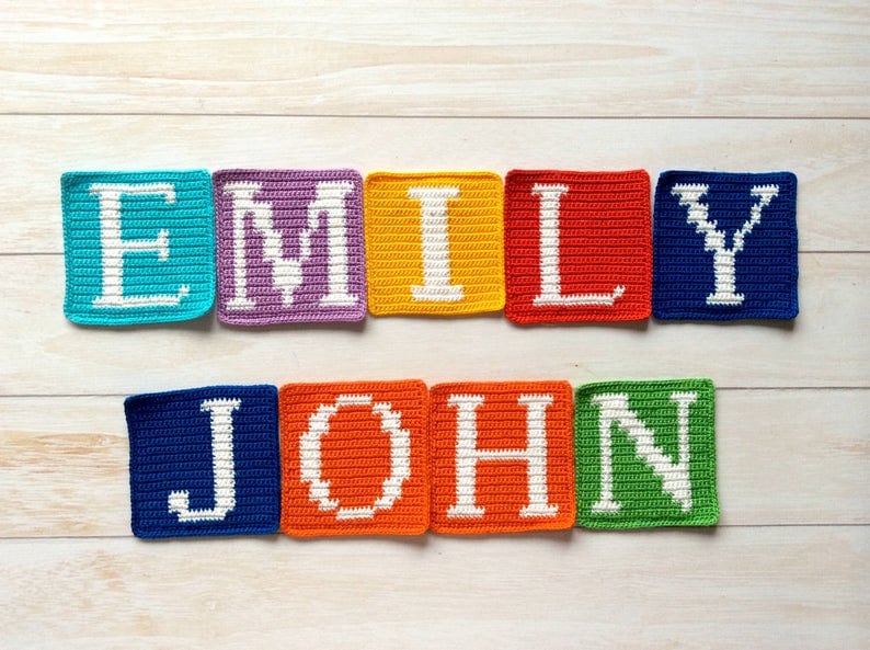 Może przedstawiać: Kwadraty na szydełku, kt&oacute;re tworzą imiona "Emily" i "John" białymi literami. Kwadraty są w r&oacute;żnych kolorach, w tym niebieskim, fioletowym, ż&oacute;łtym, czerwonym i zielonym.