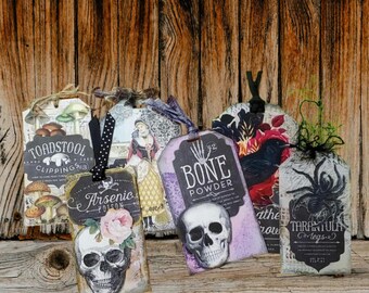May include: A collection of six rectangular paper tags featuring vintage-style illustrations of skulls, mushrooms, a crow, a spider, and a person in period clothing, with text labels including Toadstool Clippings, Arsenic, Bone Powder, and Tarantula Legs.