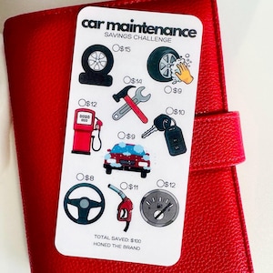 May include: A white card with the text "car maintenance SAVINGS CHALLENGE" and illustrations of car parts and services. The card is on a red leather-like surface. The card includes a steering wheel, gas pump, and car keys.