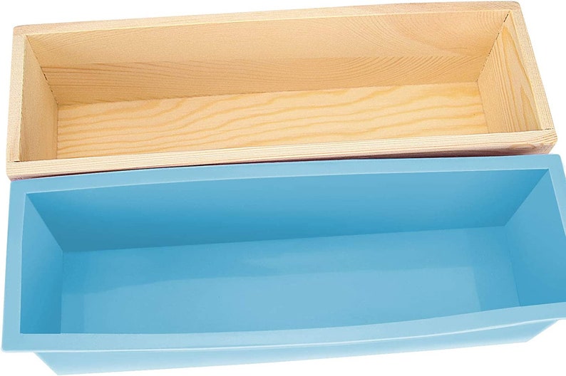 Pode incluir: Duas formas de sab&atilde;o retangulares. A forma superior &eacute; feita de madeira clara. A forma inferior &eacute; de silicone azul claro. As formas est&atilde;o vazias e prontas para uso. A forma de madeira est&aacute; acima da forma azul.