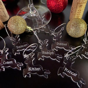 Puede incluir: Conjunto de ocho charms para copas de vino de reno de acrílico transparente con los nombres de los renos de Papá Noel: Cupido, Bailarín, Rodolfo, Trueno, Cometa, Relámpago, Brincaldo y Zorra.