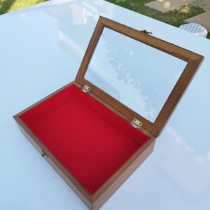 May include: A wooden display box with a glass top and a red velvet lining. The box is open and the lid is propped up.