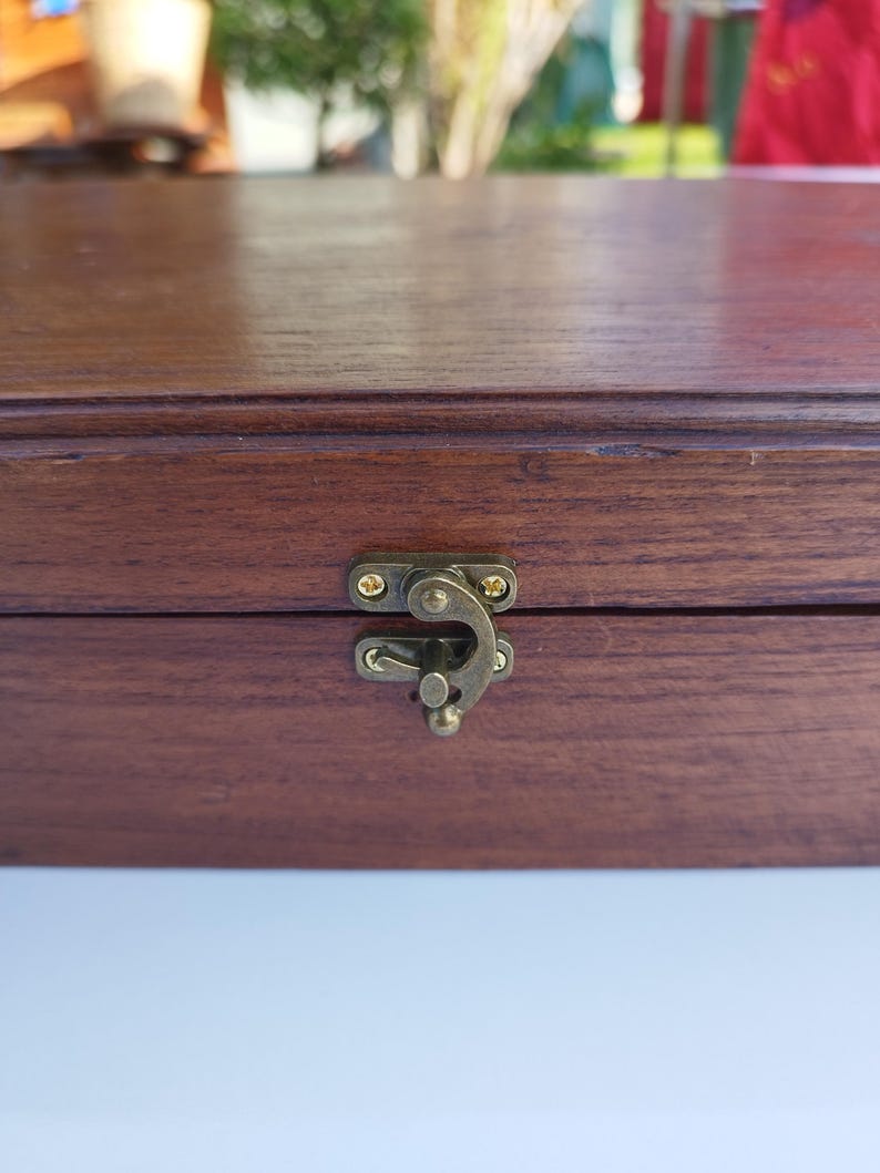 May include: A wooden box with a brass latch. The box has a dark brown stain and a smooth finish.