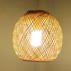 Könnte beinhalten: Eine runde, geflochtene Leuchte aus natürlichem Bambus mit einem Rautenmuster. Die Leuchte hängt von der Decke und hat eine Glühbirne im Inneren.