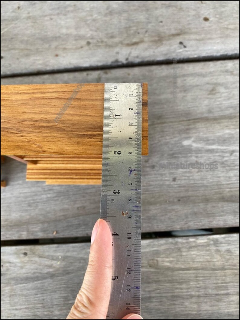 Op de afbeelding: Close-up van een houten plank die met een liniaal wordt gemeten. De liniaal toont een meting van 10 cm.