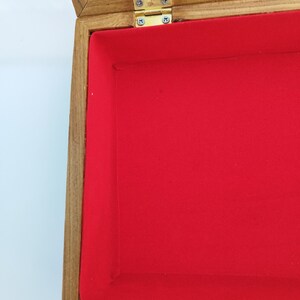 May include: A wooden display case with a glass top and a red velvet interior. The case has a brass hinge.