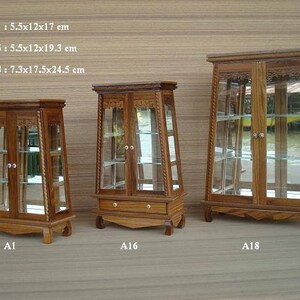 Puede incluir: Tres vitrinas de madera con puertas y estantes de vidrio. Las vitrinas son de diferentes tama&ntilde;os, la m&aacute;s peque&ntilde;a mide 14 cm por 30 cm por 43 cm, la mediana 14 cm por 30 cm por 49 cm y la m&aacute;s grande 19 cm por 44 cm por 62 cm.