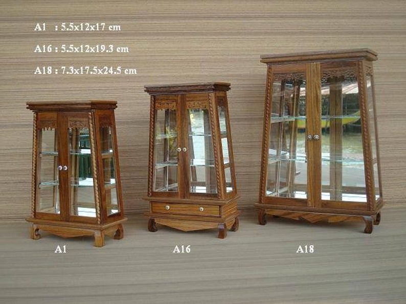 Puede incluir: Tres vitrinas de madera con puertas y estantes de vidrio. Las vitrinas son de diferentes tama&ntilde;os, la m&aacute;s peque&ntilde;a mide 14 cm por 30 cm por 43 cm, la mediana 14 cm por 30 cm por 49 cm y la m&aacute;s grande 19 cm por 44 cm por 62 cm.