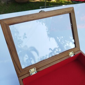 May include: A wooden box with a glass top and a red velvet interior. The box has brass hinges and a brass latch.
