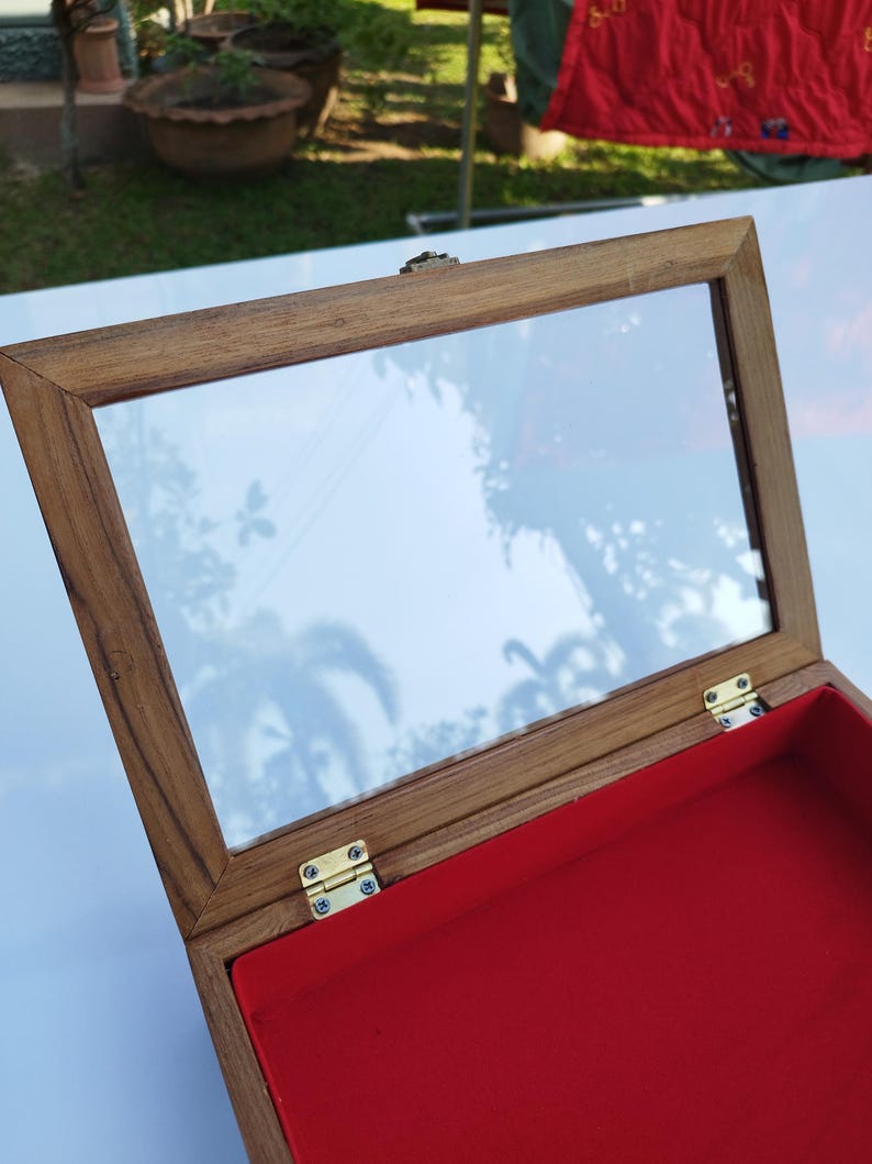 May include: A wooden box with a glass top and a red velvet interior. The box has brass hinges and a brass latch.