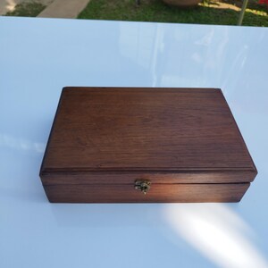 May include: A dark brown wooden box with a brass latch. The box has a smooth, polished finish and appears to be made of high-quality wood.