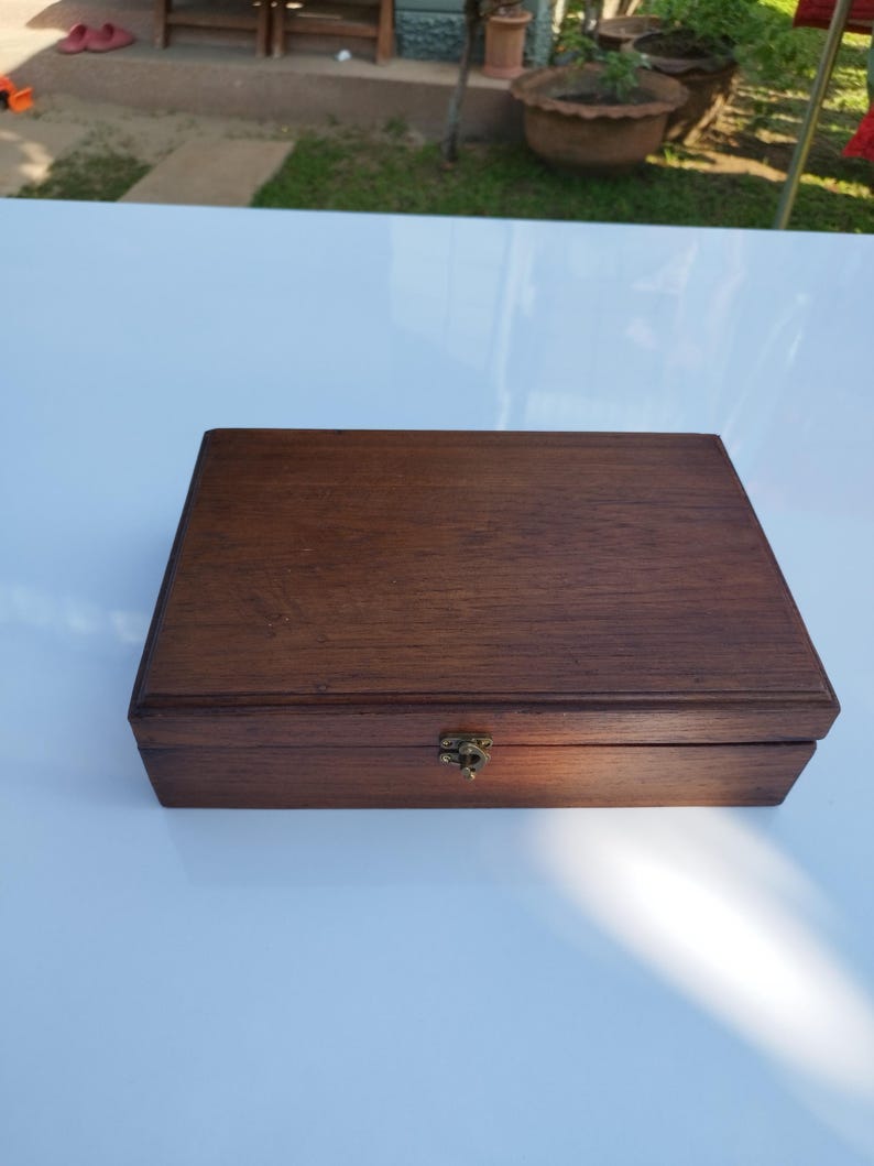 May include: A dark brown wooden box with a brass latch. The box has a smooth, polished finish and appears to be made of high-quality wood.