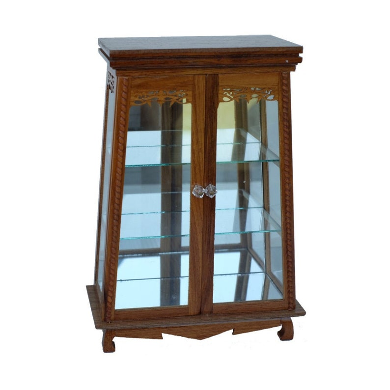 Puede incluir: Una vitrina de madera con puertas y estantes de vidrio. La vitrina tiene un acabado marr&oacute;n oscuro y tallas intrincadas en la parte delantera.