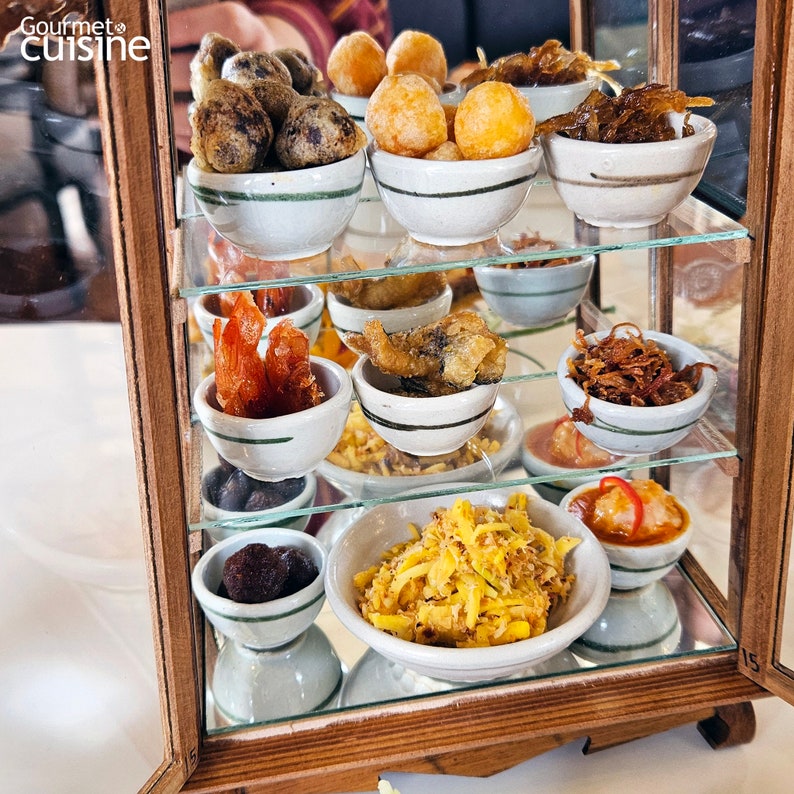Puede incluir: Un expositor de madera con varios cuencos peque&ntilde;os blancos llenos de diferentes aperitivos fritos, incluyendo pescado frito, camarones y otras delicias saladas.