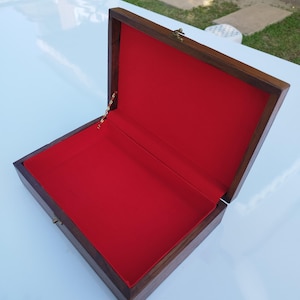May include: An open wooden box with a red velvet lining. The box has a brass latch and a gold chain.