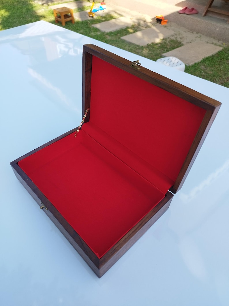 May include: An open wooden box with a red velvet lining. The box has a brass latch and a gold chain.